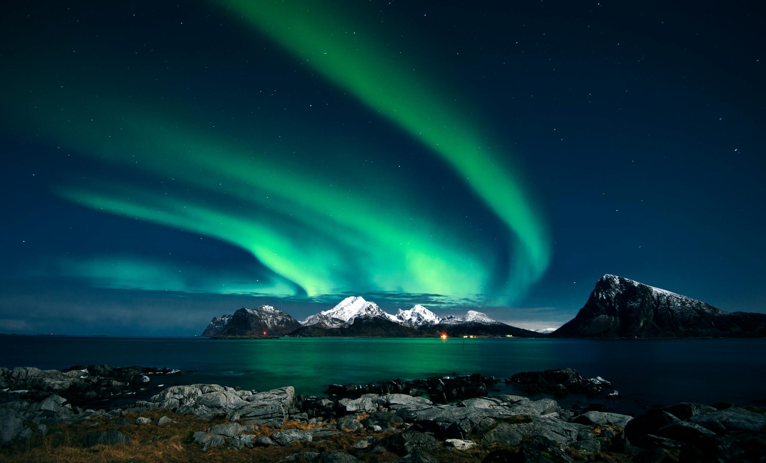 Northern lights over a mountain coastline
