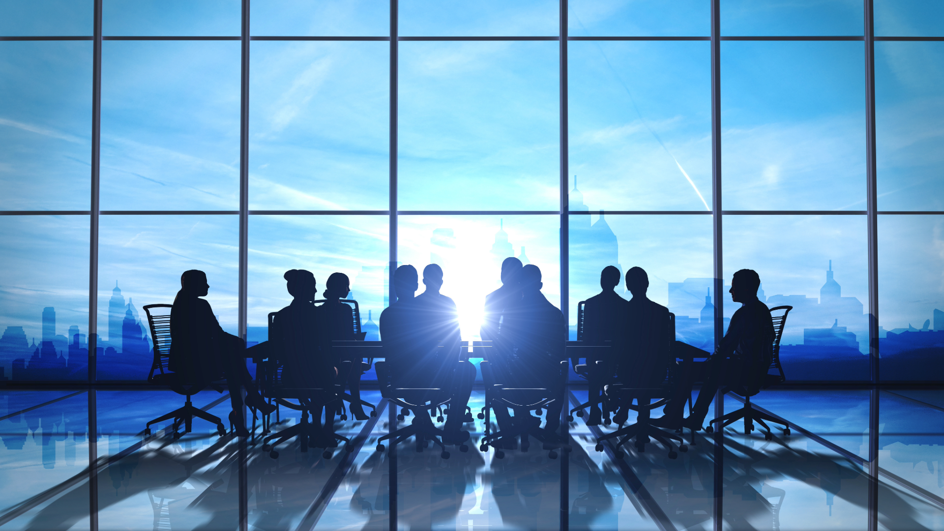 Silhouetted team seated around a conference table in a glass-walled office with a city skyline outside.